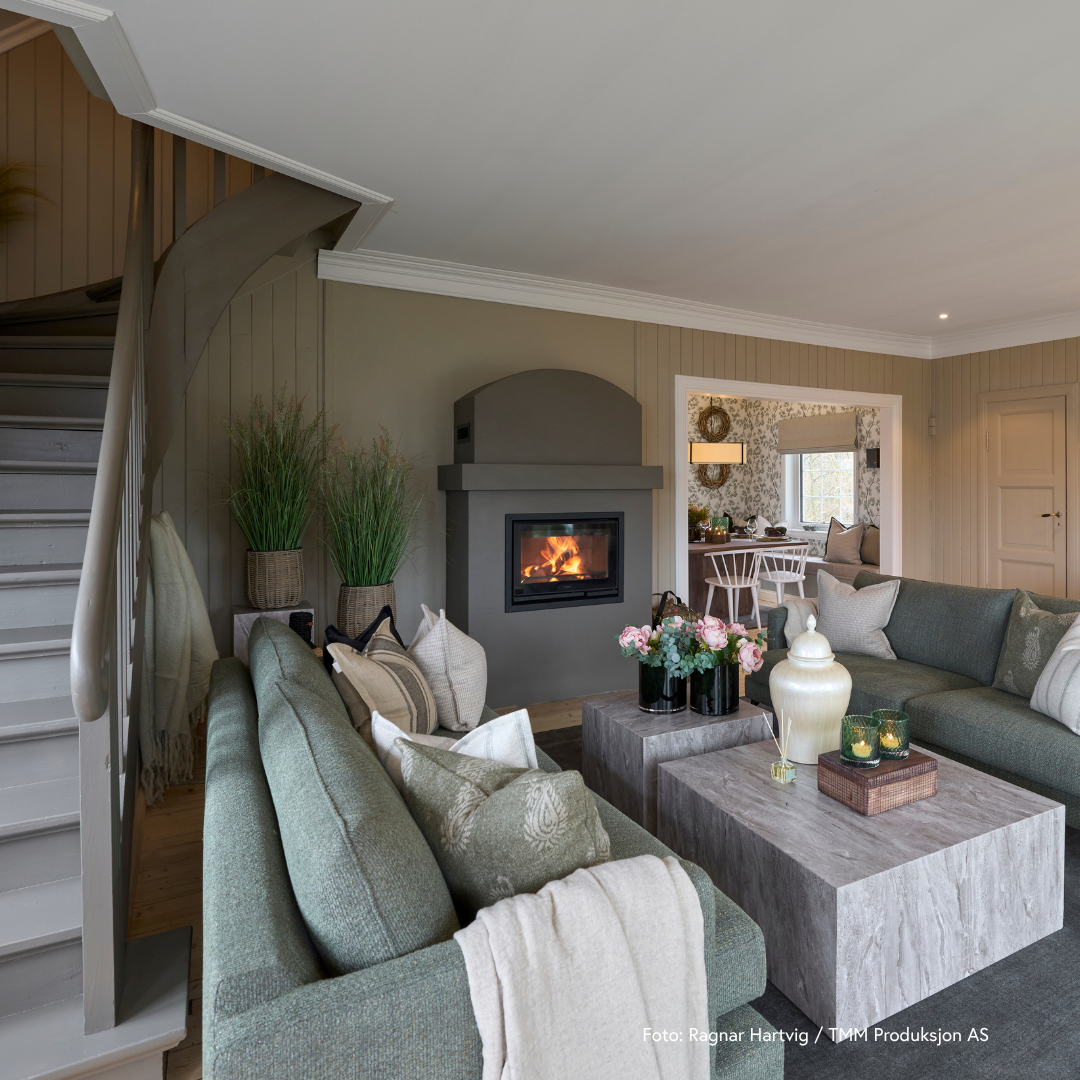 Lys og åpen stue med moderne farger og en svart peisinnsats i grå omramming