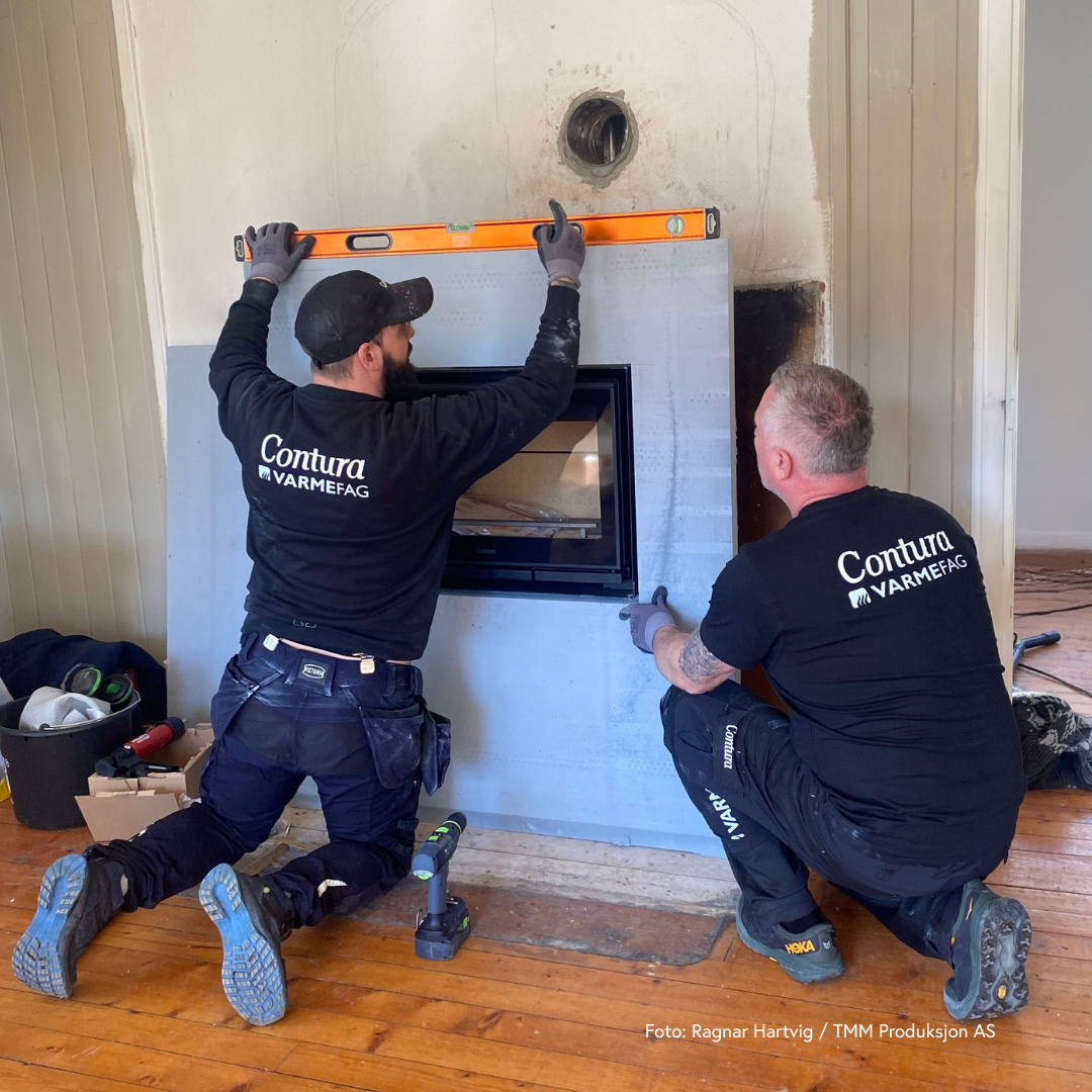 Arbeidsmenn som monterer moderne rentbrennende peisinnsats og omramming av brannmursplater