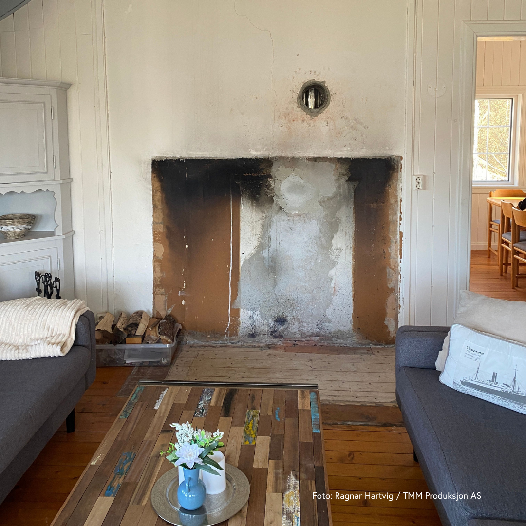 Bilde av eldre stue i fritidsbolig med åpen peis