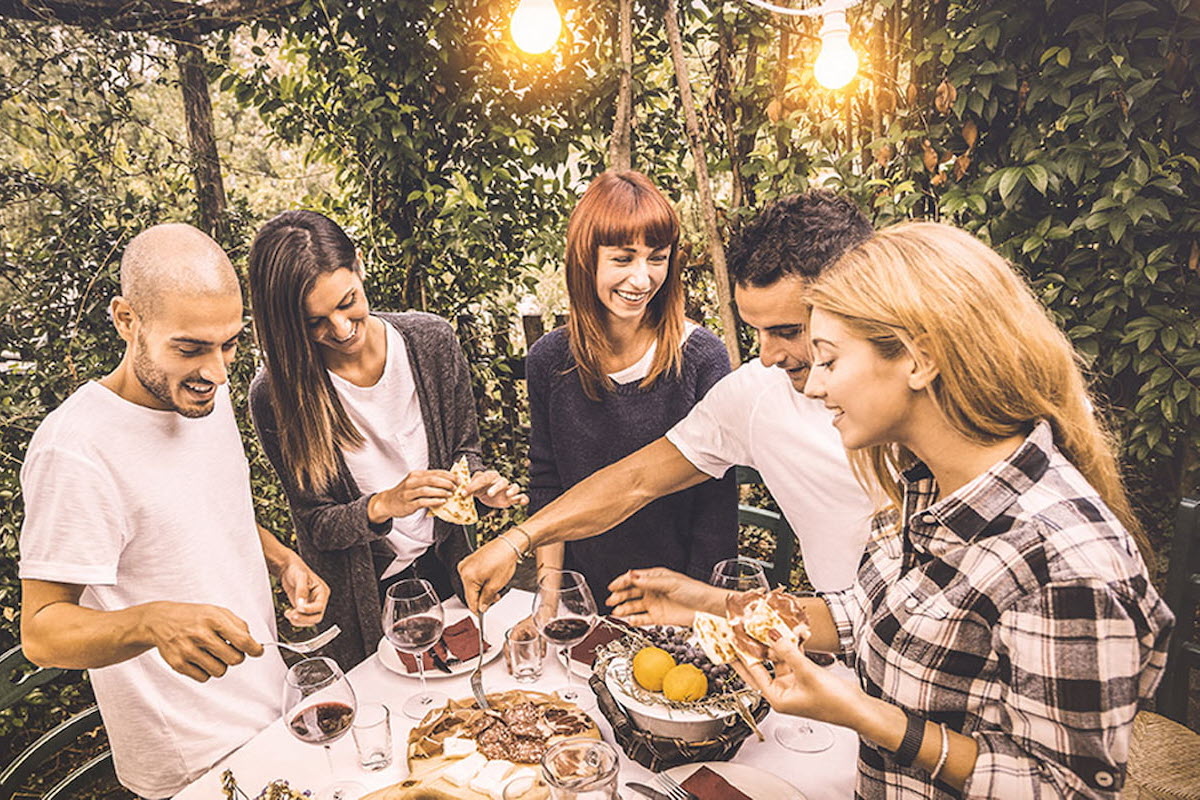 Fem mennesker samles rundt spisebordet i en hagefest