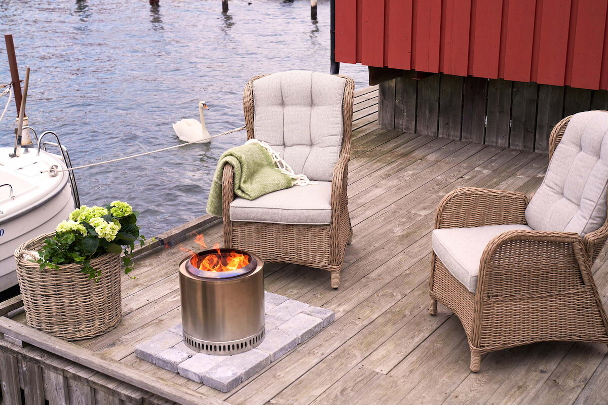 Brygge med stoler og moderne peis og utsikt til innsjø.