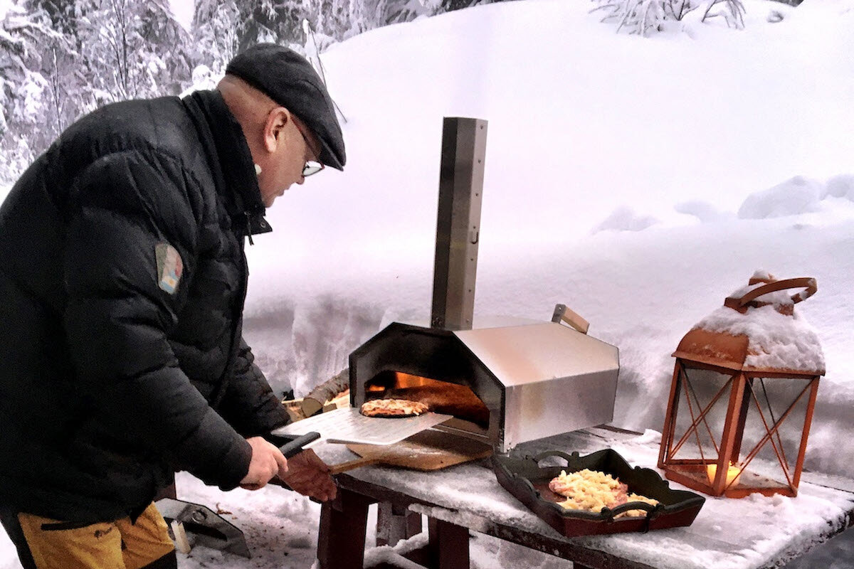 En mann som setter en pizza i en pizzaovn i vinteren