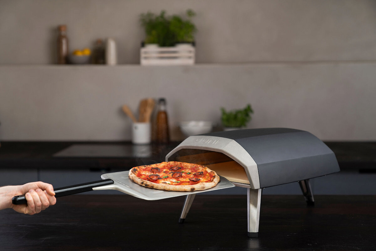 En pizza som blir satt i en pizzaovn ved hjelp av en pizzaspade