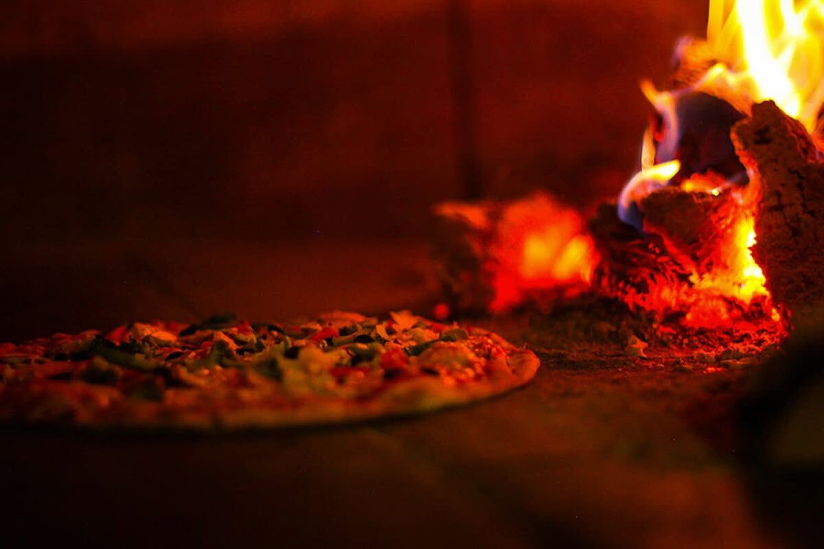 Innsiden av en pizzaovn der en pizza stekes