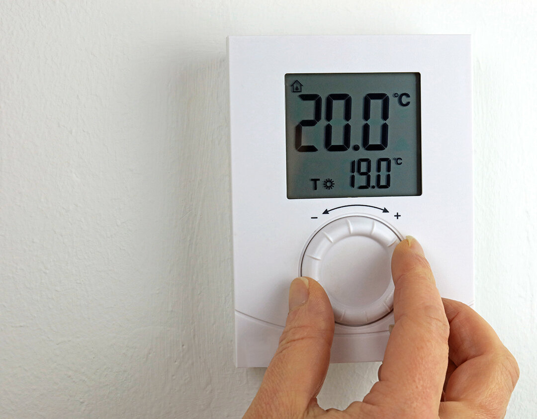 En person som senker temperaturen på en termostat