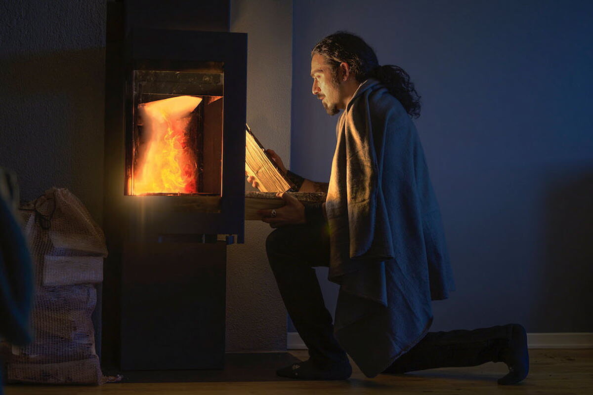 En mann som fyrer på en peisovn i mørket