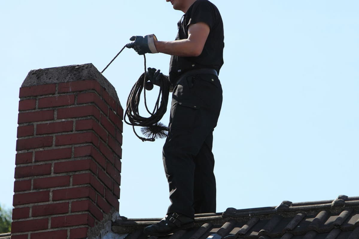 Mann feier pipa på taket til et hus