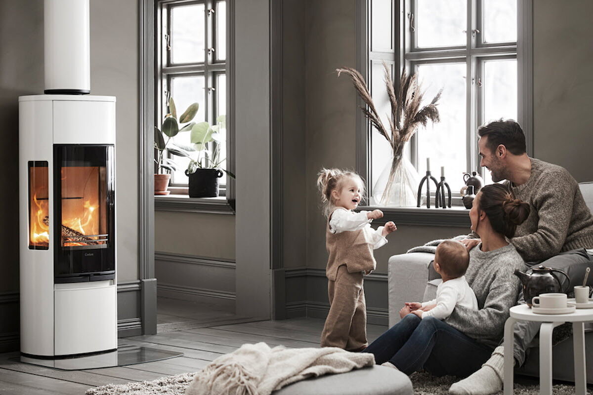 Familie med to små barn koser seg foran peisen