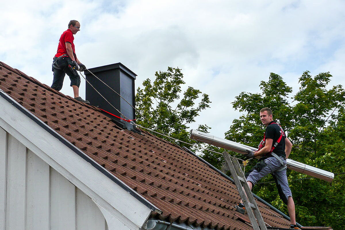 To menn som jobber med piperehabilitering på tak